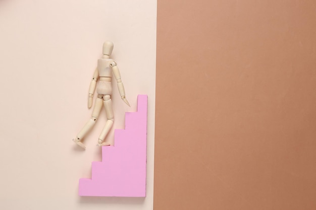 A puppet climbs up the stairs on brown beige background Career growth concept striving up