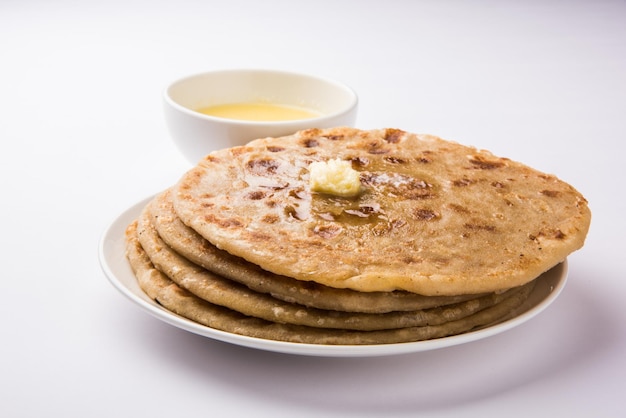 Puran Poli, also known as Holige, is an Indian sweet flatbread consumed mostly during Holi festival. Served in a plate with pure Ghee over colourful or wooden background. Selective focus