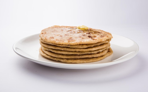 Puran Poli, also known as Holige, is an Indian sweet flatbread consumed mostly during Holi festival. Served in a plate with pure Ghee over colourful or wooden background. Selective focus