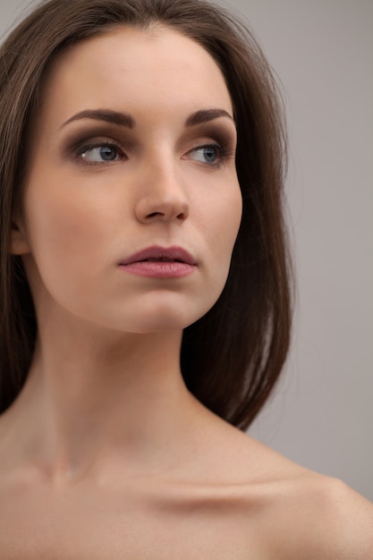 Pure beauty. Thoughtful young shirtless woman looking away while isolated on grey background