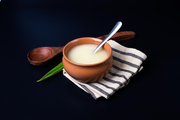 Pure cow ghee in ceramic bowl on black background with ghee spoon in hand