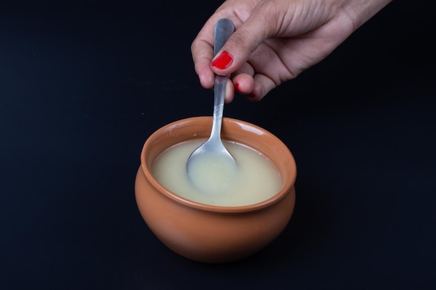 Pure cow ghee in ceramic bowl on black background with ghee spoon in hand