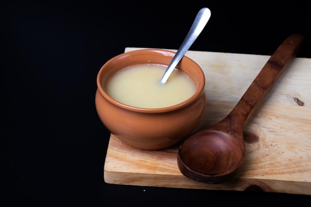 Pure cow ghee in ceramic bowl on black background with ghee spoon in hand