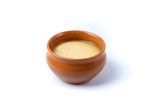 Pure cow ghee in ceramic bowl on white background