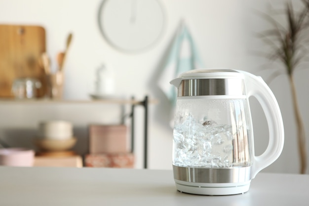 Pure water boils in an electric kettle on the table in the kitchen