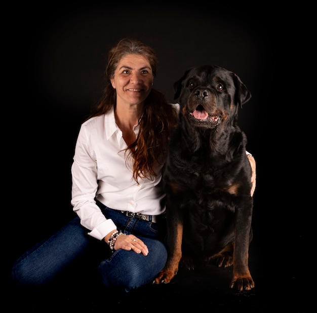 Purebred rottweiler and woman in front of black surface