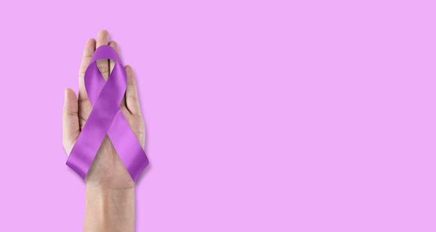 Purple awareness ribbon for World cancer day and World Alzheimers day month concept bow on helping hand support isolated