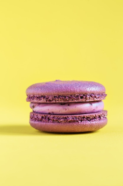 purple cake macaron or macaroon on yellow wall. colorful almond cookies. french macaroon