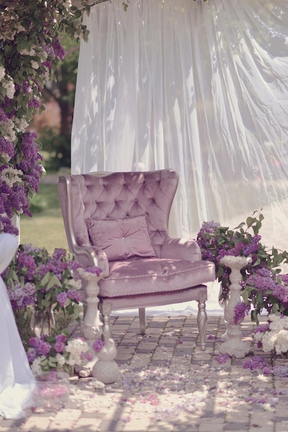 A purple chair is on a patio with purple flowers.