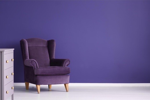 A purple chair in a white room with a white wall that says'blue'on it.