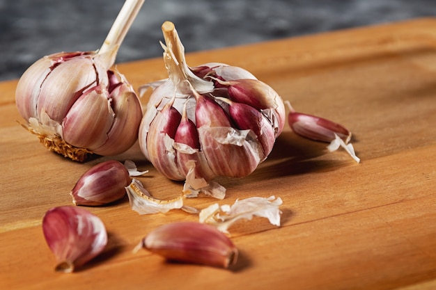 Purple garlic bulb, used in food as a seasoning or in health as a remedy. Dark background on wooden base. Space intended for text.