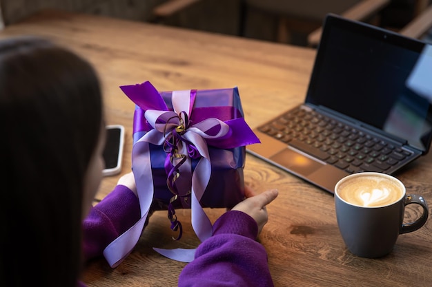 Purple gift box in a womans hands in a purple sweater