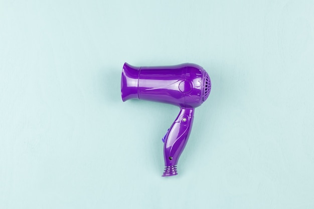 Purple hair dryer on blue wooden surface