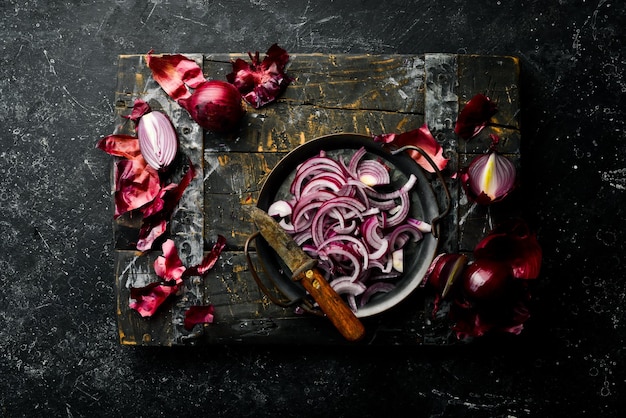 Purple onion Fresh chopped onions on a wooden board Top view On a black stone background