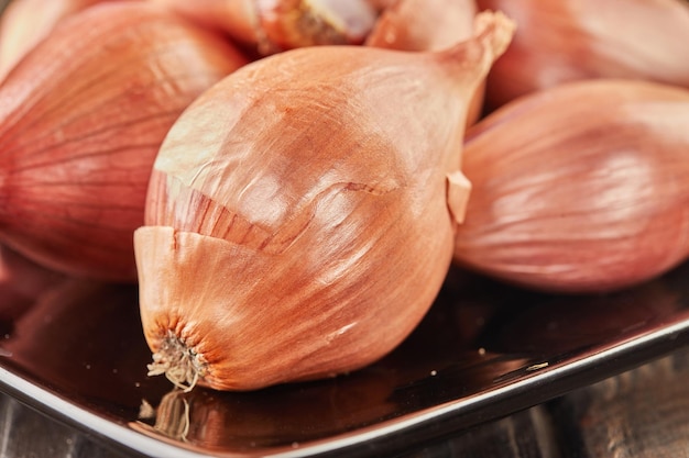 Purple onion lies on black plate on wooden background