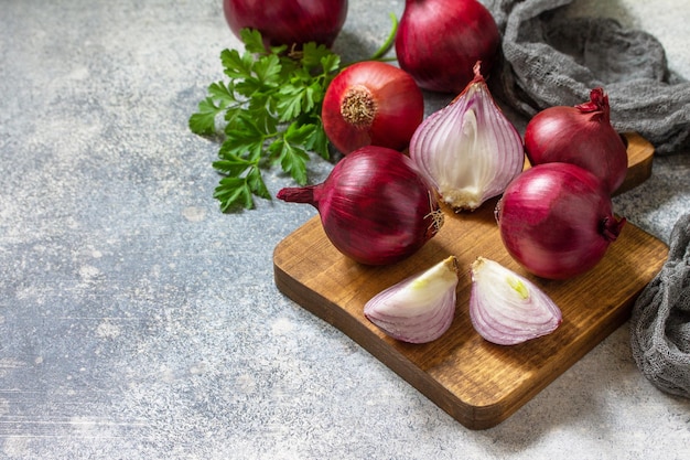 Purple Onions Fresh whole purple onions and one sliced onion on a stone countertop Copy space