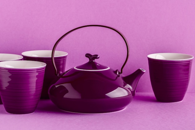 Purple teapot and cups on a lilac background