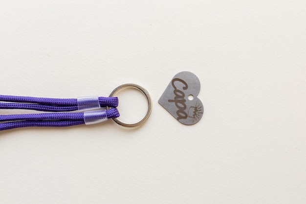 A purple and white keychain with the word cap on it.