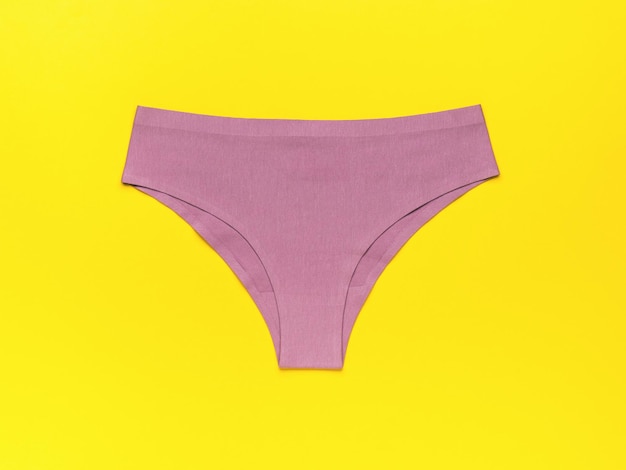 Purple women's panties on a bright yellow background The concept of women's underwear