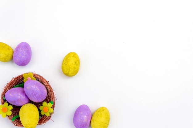 Purple and yellow Easter eggs in a nest on a white background View from above Copy space