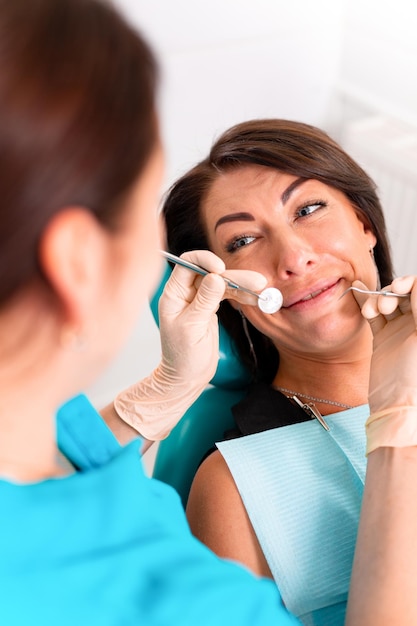 Putting dental braces to the womans teeth at the dental office Dentist examine female patient with braces in dental office Closeup of a young attractive girl with braces on the teeth