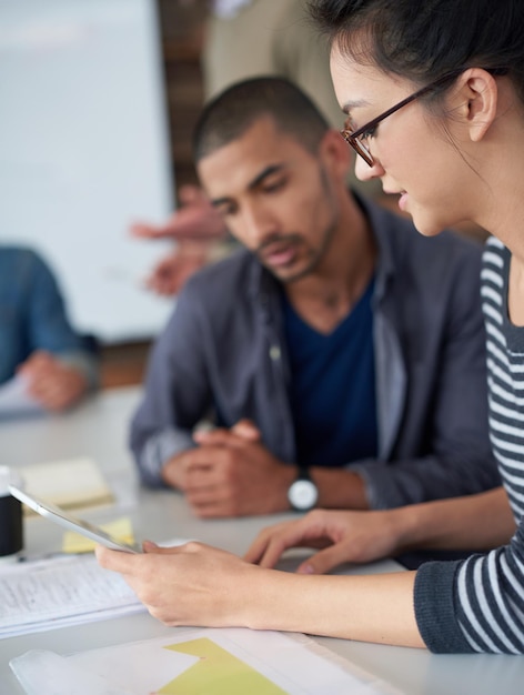 Putting two heads together Shot of two coworkers sitting at a table in an office using a digital tablet