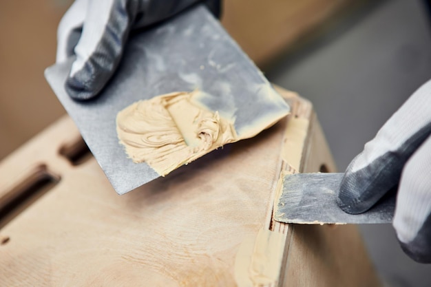 Putty of wood Manual worker spackling wooden products at the carpentry manufacturing Close up of working process