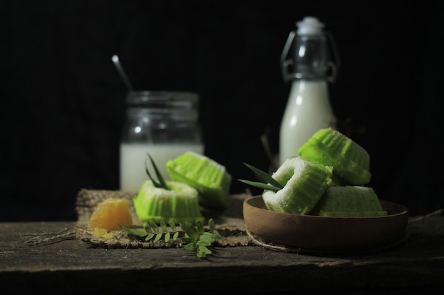 Putu cake on a wood plate with milk and brown sugar