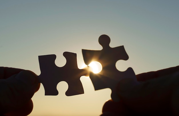 puzzle pieces are connected puzzle pieces in hand on a sunny sky background business partner