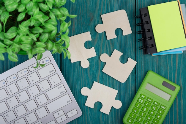 Puzzle pieces calculator sketchbook computer keyboard on a blue wooden background