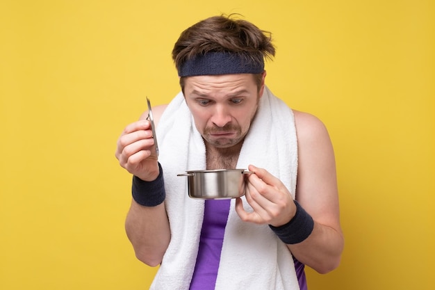 Puzzled man looking on food in small pan being upset with his dinner