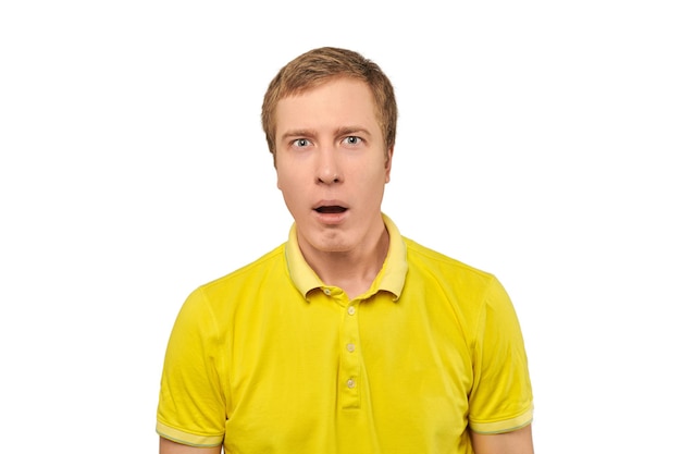 Puzzled young man with funny face and open mouth in yellow Polo Tshirt white isolated background