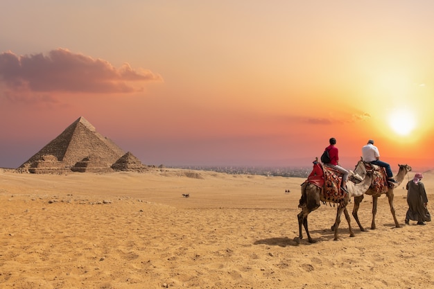 The Pyramid complex of Giza and arabs on camels, Egypt.