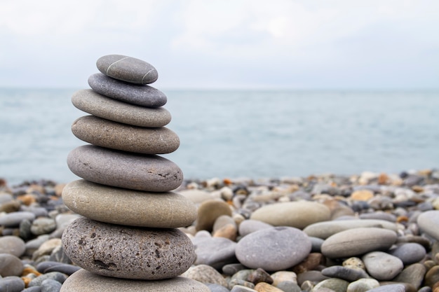 Pyramid of sea stones on the seashore at the pebble beach. Concept of harmony and balance.