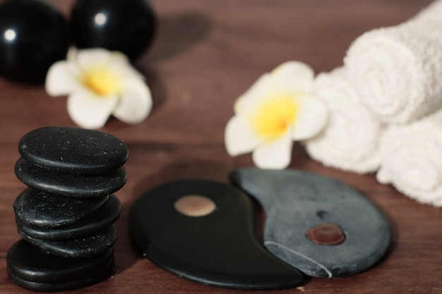 Pyramid of stones for hot massage in black on the table with spa composition and burning candles