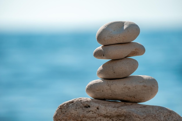 Pyramid stones on the seashore on a sunny day on the blue sea background happy holidays pebble beach