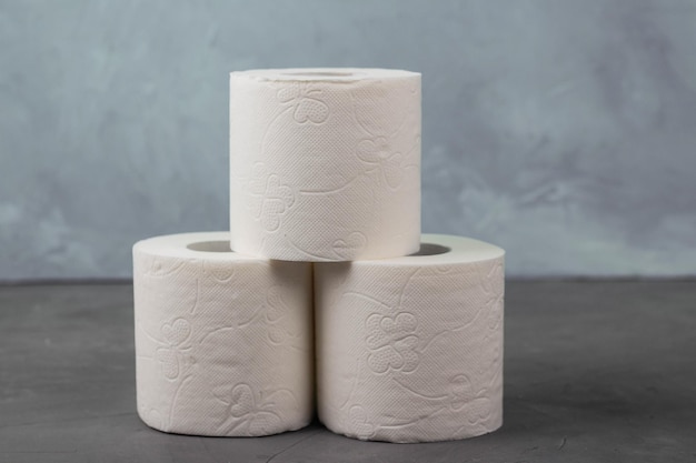 Pyramid of three toilet paper rolls on a gray background