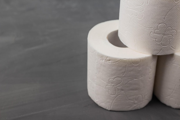 Pyramid of three toilet paper rolls on a gray background