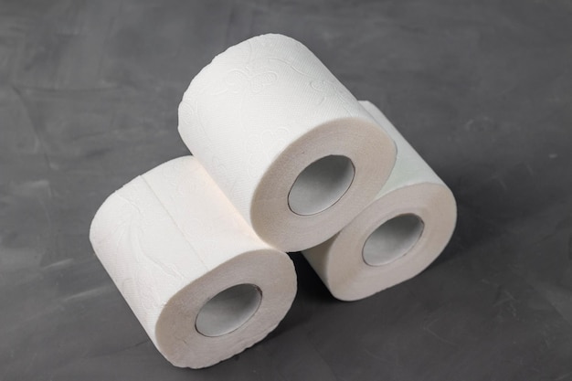 Pyramid of three toilet paper rolls on a gray background