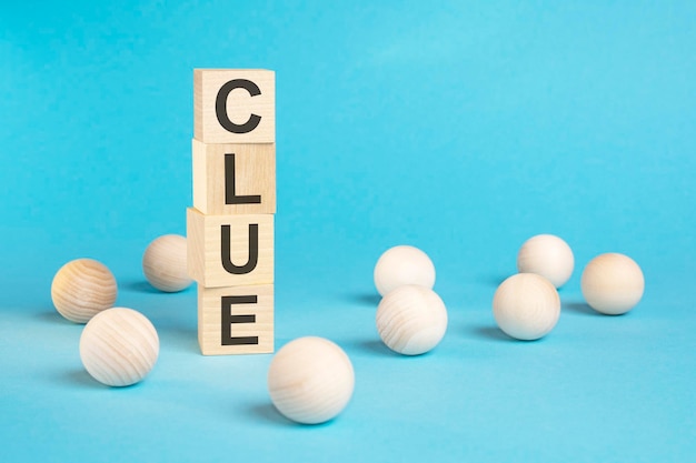 Pyramid of wooden cubes with the word CLUE and wooden balls on a blue background