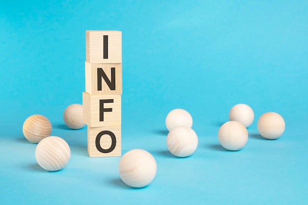 Pyramid of wooden cubes with the word INFO and wooden balls on a blue background