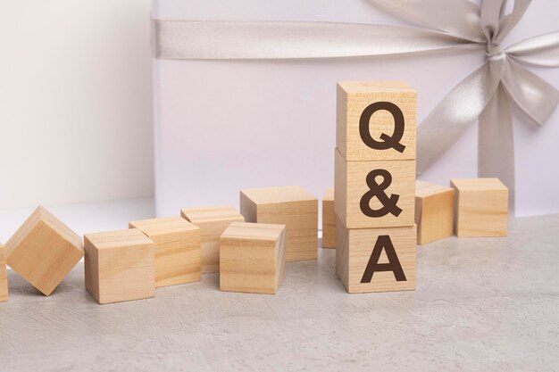 Qa letters on wooden cubes concept on white gift box background