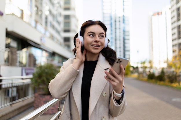 Qafqazinfo a strong woman listens to music in headphones using a phone on the background of the city