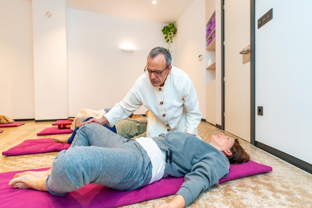 Qi gong teacher correcting a woman during meditation class