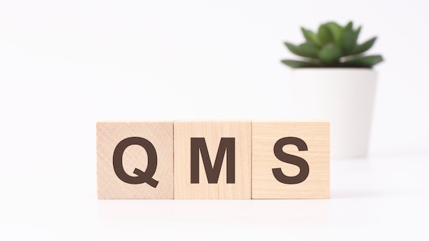 QMS text on wooden cubes white background business concept