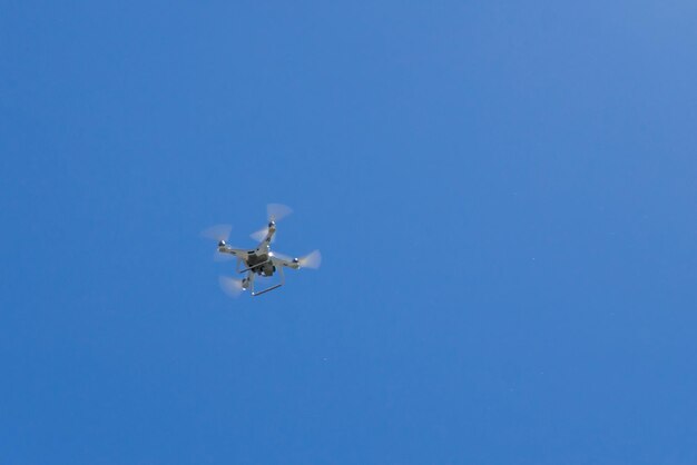 Quadcopter drone with the camera hovering in blue sky