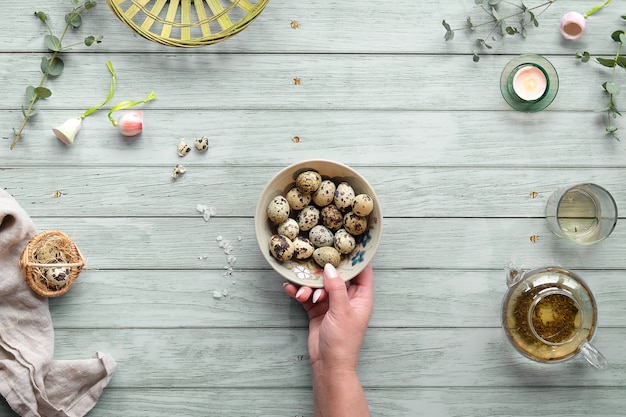 Quail Easter eggs and natural Spring decorations and eucalyptus twigs on mint green wood.