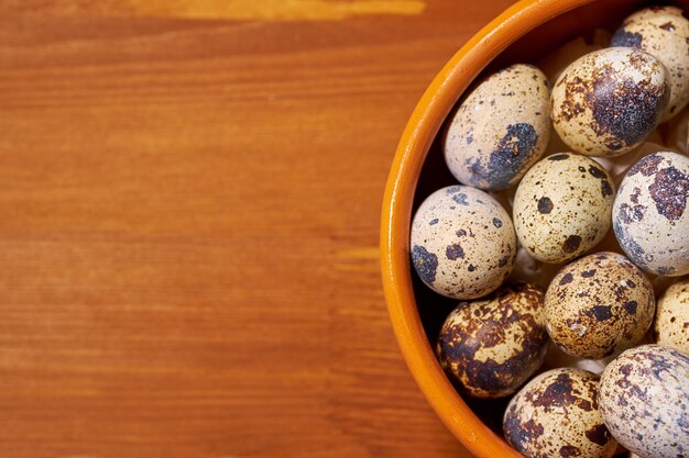 Quail eggs in clay bowl on brown wood