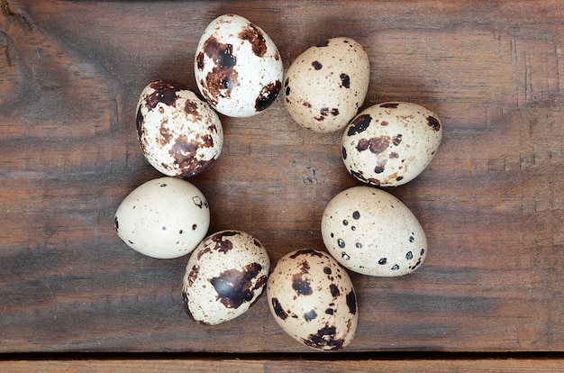 Quail eggs on a dark brown wooden surface, top view, empty place for text, recipe