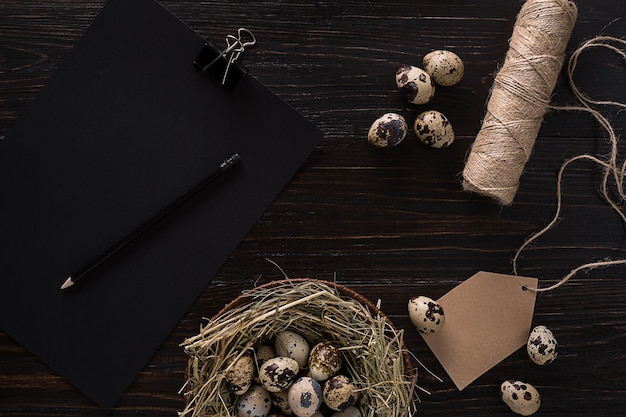 Quail eggs in nest notebook and thread on a black background